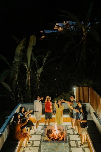 a group of people standing around a fire in a pool at Glamping tent in Pelaga Eco Park in Patjung