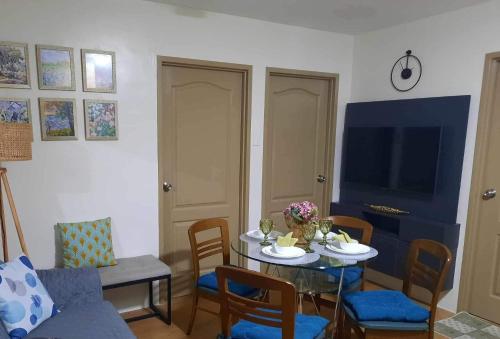 a living room with a table with chairs and a tv at Two-Bedroom Condo Retreat in Manila