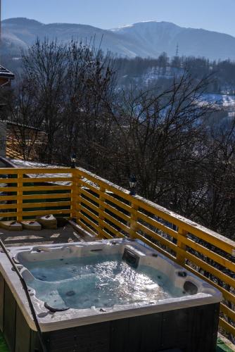 a jacuzzi tub on a deck with a fence at ȘURA LU' PĂTRU in Vulcan