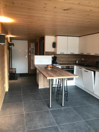 une cuisine avec des armoires blanches et un plafond en bois dans l'établissement Bel appartement neuf équipé au pied des pistes du HONHECK, à La Bresse
