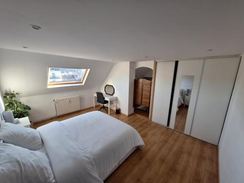 a bedroom with a large white bed and a mirror at Les Combles de Bagnères in Bagnères-de-Bigorre