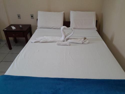 Una cama blanca grande con una toalla. en Pousada Ventos Do Mar, en Natal