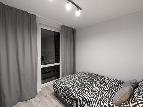 a bedroom with a black and white bed and a window at SunApart A182 in Warsaw