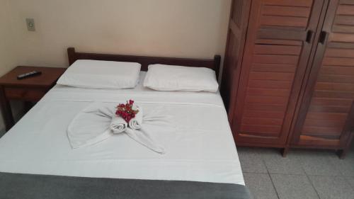 a white bed with a white ribbon and flowers on it at Pousada Ventos Do Mar in Natal