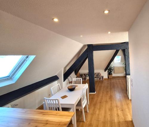 une salle à manger avec une table et des chaises blanches dans l'établissement Les Combles de Bagnères, à Bagnères-de-Bigorre
