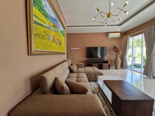 a living room with a couch and a tv at Villa Norwegia - pool with panorama rice field view in Yogyakarta