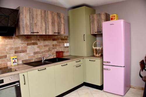 une cuisine avec des placards blancs et un réfrigérateur rose dans l'établissement Chez Montgaud, à Verdun-sur-Meuse
