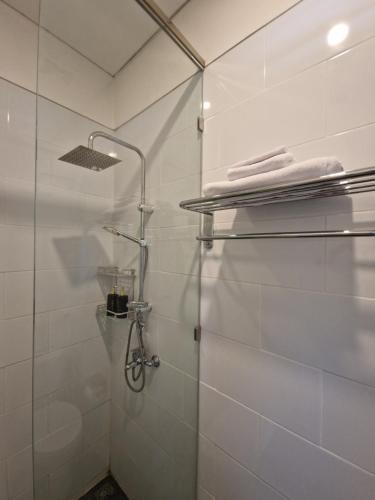 a bathroom with a shower with white tiled walls at Villa Norwegia - pool with panorama rice field view in Yogyakarta