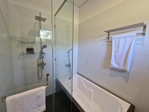 een badkamer met een douche, een bad en een wastafel bij Villa Norwegia - pool with panorama rice field view in Yogyakarta
