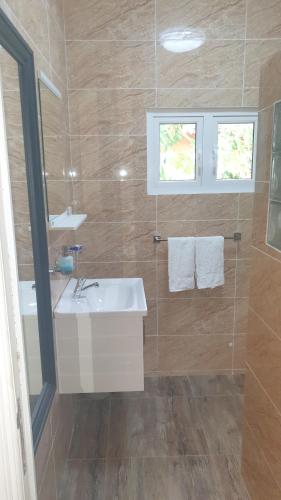 Un baño con lavabo blanco y ducha. en Kaiselfcatering, en La Réunion