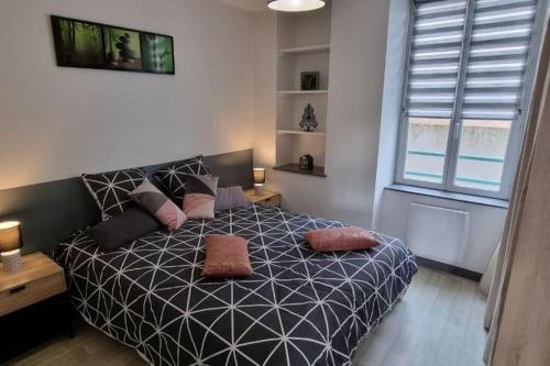 a bedroom with a black and white bed with pillows at Superbe appartement avec parking in Saint-Junien