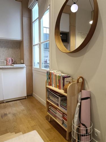un miroir suspendu au-dessus d'une étagère avec des livres dans l'établissement Studio cosy Paris 6ème Bon Marché, à Paris