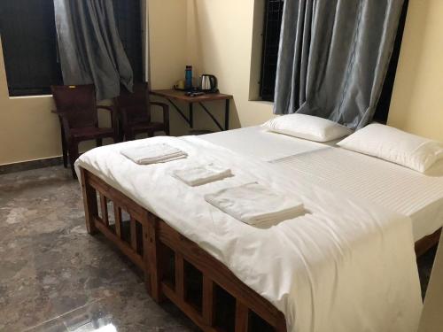 a bedroom with a large bed with white sheets at Swarga Homestay in Mangalore