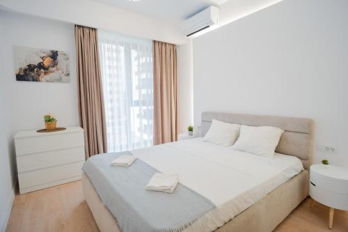 - une chambre blanche avec un grand lit et une fenêtre dans l'établissement X Metropolitan Retreats 2BR in Politehnica Park, à Bucarest