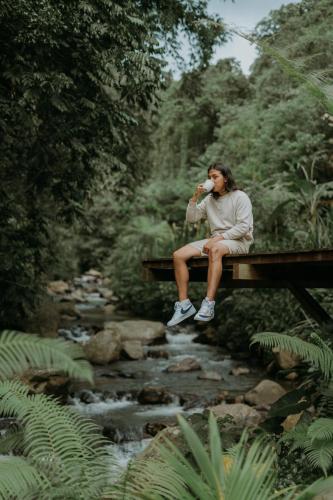 a person sitting on a picnic table next to a creek at Glamping tent in Pelaga Eco Park in Patjung
