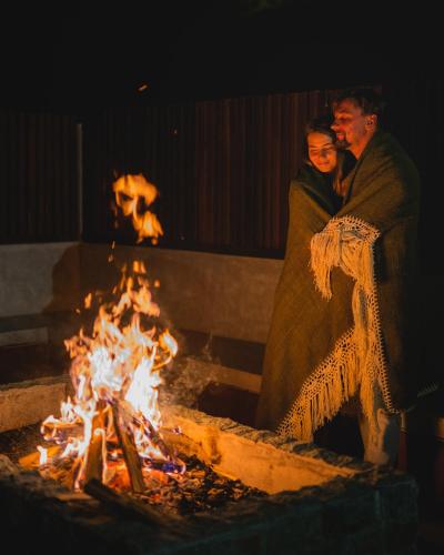 a man and a woman standing next to a fire at Glamping tent in Pelaga Eco Park in Patjung