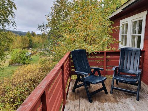 two chairs sitting on the porch of a red house at Vikinggård Cottages in Höljes