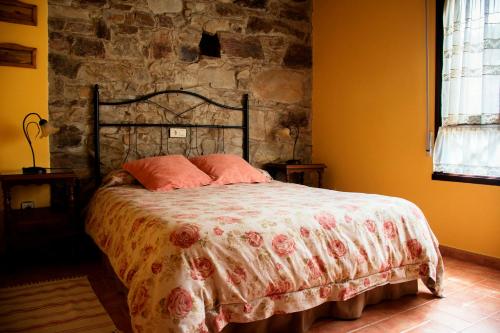 a bedroom with a bed with a stone wall at Apartamentos El Cueto in Oviñana