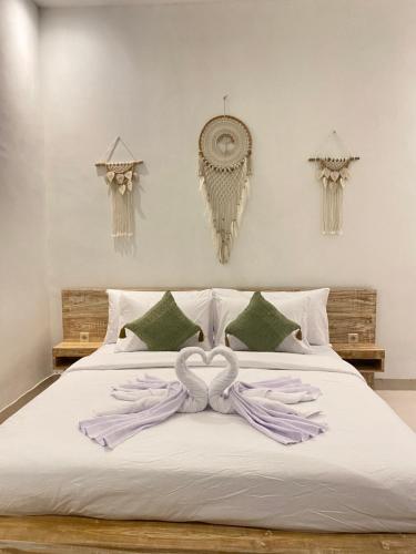 a white bed with a heart shaped towel on it at La vida Bali in Kubupenlokan