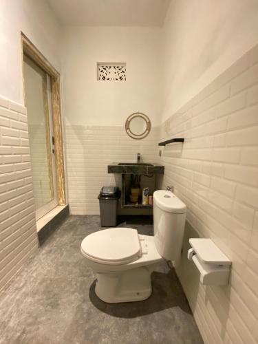 a bathroom with a white toilet and a mirror at La vida Bali in Kubupenlokan