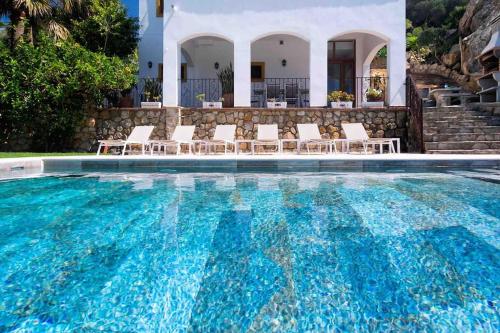a swimming pool with chairs and a house at Villa Alta Vista in Zahara de los Atunes
