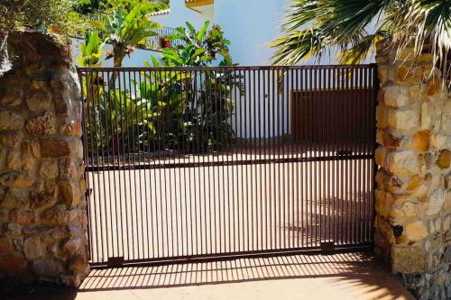 an iron gate with a stone wall and palm trees at Villa Alta Vista in Zahara de los Atunes