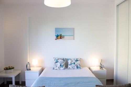a white bedroom with a bed and two tables at Casa dos Arcos BeachStudio by CC 904 in Portimão