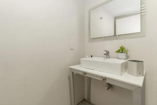 Baño blanco con lavabo y espejo en Monoambiente moderno con Amenities Nuñez en Buenos Aires
