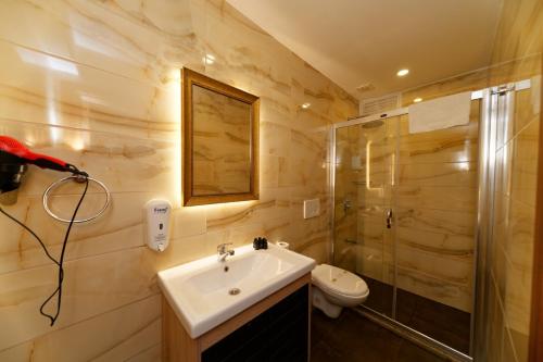 La salle de bains est pourvue d'un lavabo, de toilettes et d'une douche. dans l'établissement Kral Suit Apartment & Hotel, à Istanbul