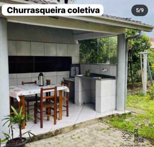 uma cozinha exterior com mesa e cadeiras em Pousada Pé na Praia em Imbé