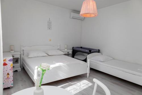 a white room with two beds and a table at Holiday house "Dolka" in Postira