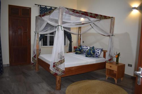 a bedroom with a canopy bed and a window at Kili Kivuli in Msaranga