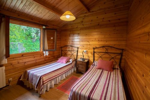 a bedroom with two beds in a log cabin at Apartamentos El Cueto in Oviñana