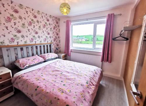 a bedroom with a pink bed and a window at The Annex in Cemaes Bay