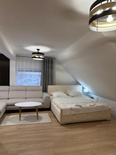 a white bedroom with a bed and a couch at Motel Za Miedzą in Bralin