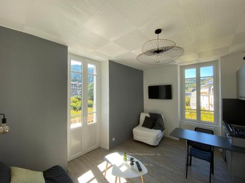 - un salon avec une table, un canapé et des fenêtres dans l'établissement Studio 17, à La Bourboule