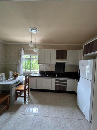 a kitchen with a white refrigerator and a table at Acomodação vó Nilton in Governador Celso Ramos