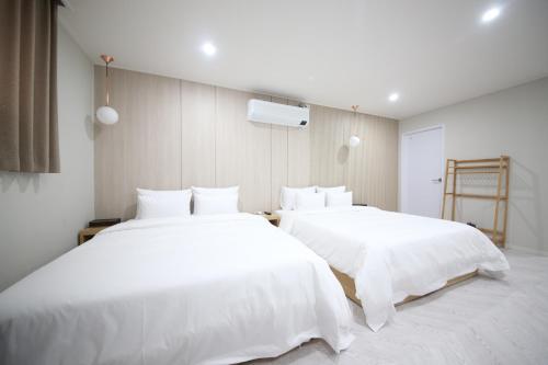 two beds in a room with white sheets at HARU Hotel in Changwon