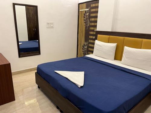 1 dormitorio con cama azul y espejo en ARNAV GUEST HOUSE, en Gorakhpur
