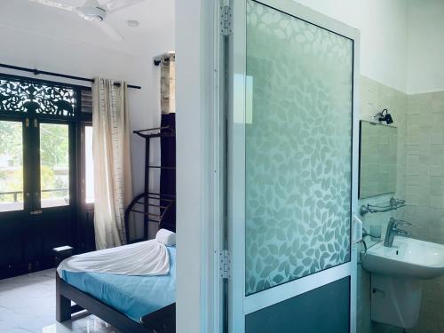 a bathroom with a glass shower with a sink and a bed at Center Point Villa Unawatuna in Unawatuna