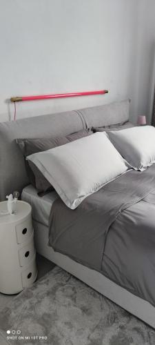 Una cama con almohadas blancas y un estante encima. en B&B Al 27, en Paderno dʼAdda