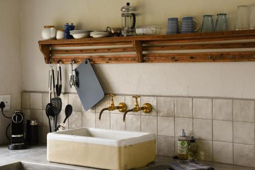 eine Küche mit einem Waschbecken und einem Regal mit Geschirr in der Unterkunft Eikehof Farm in Worcester