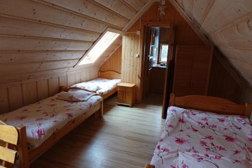 a attic room with two beds and a window at Domek Białka Tatrzańska in Białka Tatrzańska