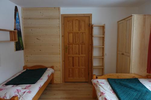 a room with two beds and a wooden door at Domek Białka Tatrzańska in Białka Tatrzańska