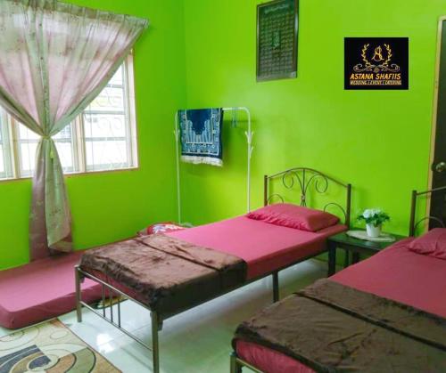 a green room with two beds and a window at ASTANA SHAFIIS in Malacca
