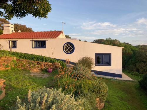 a white house with a window and a yard at Herdade AMÁLIA RODRIGUES in Zambujeira do Mar