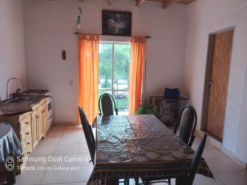 stół i krzesła w kuchni z oknem w obiekcie Nancy's Residencias w mieście Santa Rosa de Calamuchita