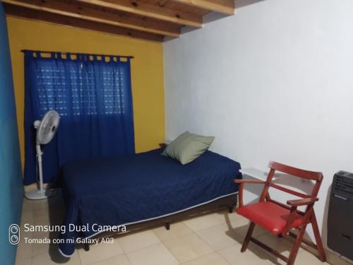 sypialnia z niebieskim łóżkiem i czerwonym krzesłem w obiekcie Nancy's Residencias w mieście Santa Rosa de Calamuchita