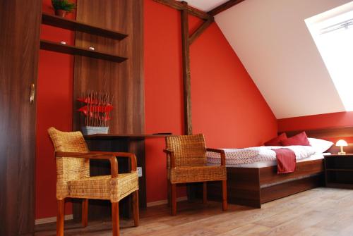 チェイコヴィツェにあるVinařství Pastorekの赤い壁のベッドルーム1室、ベッド1台(椅子2脚付)