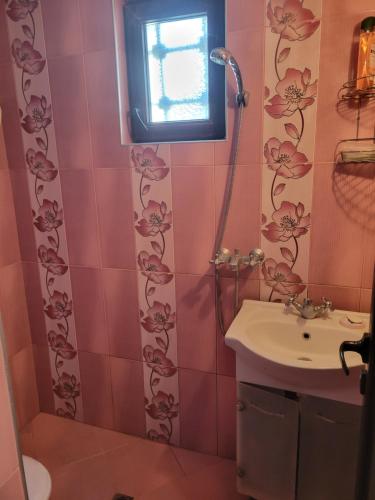 a pink bathroom with a sink and a window at Вила Рени in Varna City